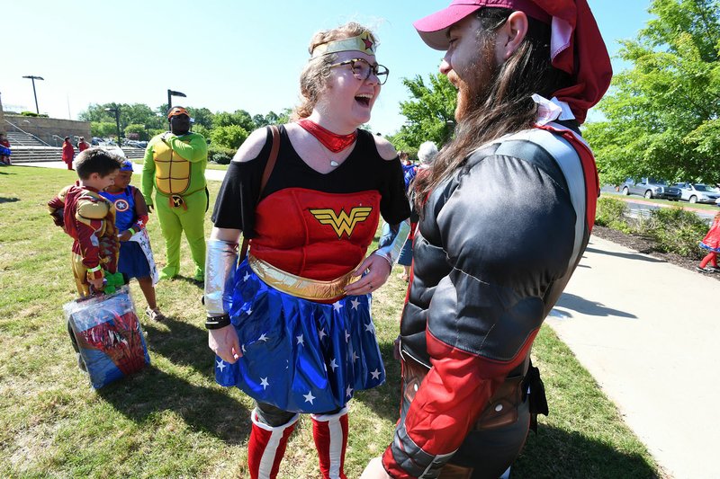 Paige Dew (left) of Bentonville dressed as Wonder Woman and Stephen Miller of Rogers dressed as Deadpool laugh Sunday while waiting to enter the stadium for the A League of Their Own reunion softball game at Arvest Ballpark in Springdale. The event concluded the Bentonville Film Festival. More than a thousand people dressed in costume were attempting set a world record for most people dressed as super heroes but fell more than 500 people short.