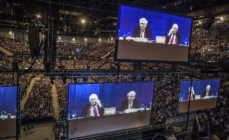 Berkshire Hathaway Chairman and Chief Executive Officer Warren Buffett and Vice Chairman Charlie Munger (in red tie) are shown on large video screens Saturday as they preside over the company’s shareholders meeting in Omaha, Neb.
