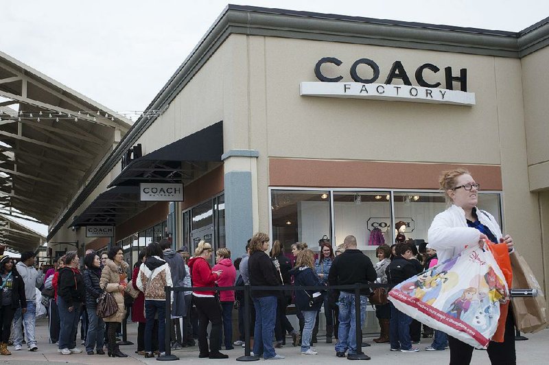 Shoppers stand outside a Coach factory outlet store in Monroe, Ohio, in this file photo. Coach announced Monday that it is buying Kate Spade in a $2.4 billion deal.