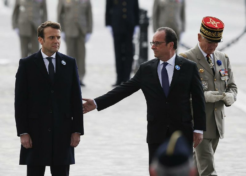 French President Francois Hollande reaches out to President-elect Emmanuel Macron on Monday during a ceremony in Paris to mark Victory Day, a commemoration of Germany’s defeat in World War II.