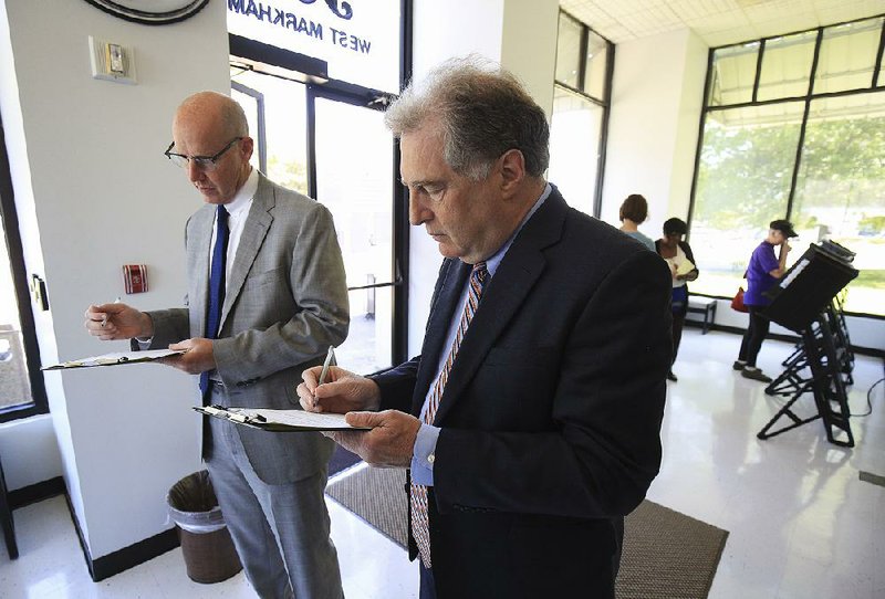 Steve Lancaster (left) and Ed Lowther fill out voting forms Monday afternoon on the final day of early polling on the Little Rock School District’s millage-extension proposal. Today, residents can go to their polling places to vote.