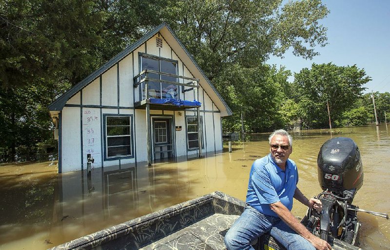 Butch Rice pilots a boat Monday past a home in the Spring Lake area of Des Arc, where the water level has risen to nearly 35 feet, 4 feet lower than the record mark of 39.4 feet set in 2011. More photos are available online at arkansasonline.com/galleries.