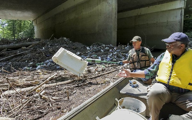 Longtime cleanup volunteer Cowper Chadbourn and John Isom of Little Rock snag trash Monday from Fourche Creek near the Mabelvale Pike overpass. The creek, which runs through south Little Rock, has been designated as the state’s fi rst Urban Water Trail.