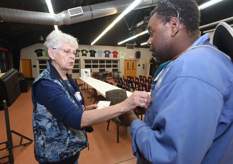 NWA Democrat-Gazette/FLIP PUTTHOFF Poll worker Winona Woods places an &#8220;I Voted&#8221; sticker on Jesse Bray after Bray voted Tuesday in the school millage election at First Baptist Church in Pea Ridge. Poll workers in Pea Ridge reported a steady stream of voters.