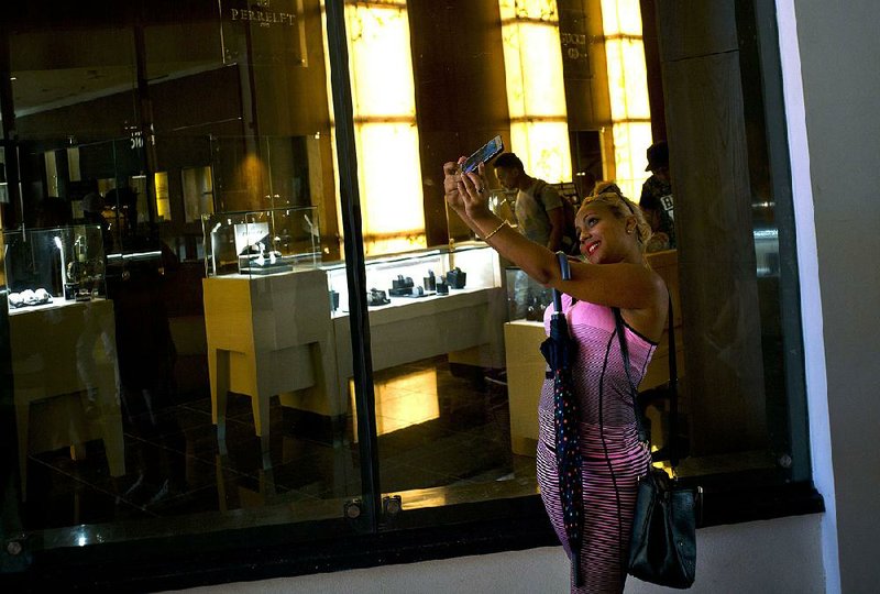 A Cuban woman takes a selfie in front of a luxury goods store at the Manzana de Gomez mall in Havana on Monday. 