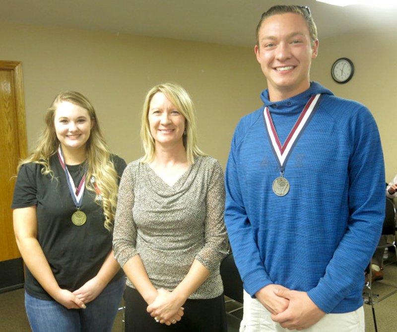 Photo by Susan Holland Two members of the HOSA club at Gravette High School who were winners in HOSA state competition were present at the April meeting of the Gravette school board and led the Pledge of Allegiance to open the meeting. Pictured are Casey Ogle (left), state gold medal winner in veterinary science; Dane Hilger, state silver medal winner in pharmacology; and, Robin Hilger (center), RN, their medical professions instructor and HOSA sponsor.