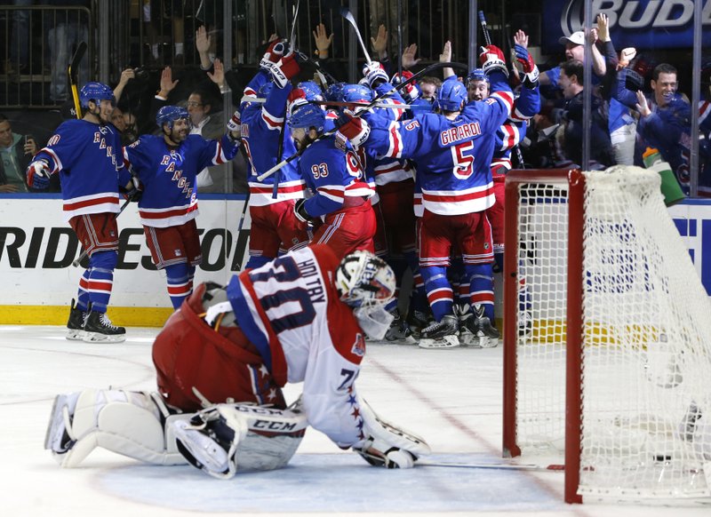 In this May 13, 2015, file photo, the New York Rangers celebrate the game winning goal by center Derek Stepan (21) against the Washington Capitals as Capitals goalie Braden Holtby looks at the puck in the net in overtime of Game 7 of the Eastern Conference semifinals during the NHL hockey Stanley Cup playoffs in New York. 