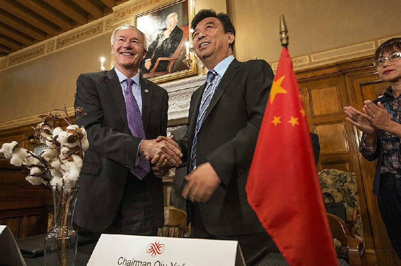 Gov. Asa Hutchinson stands with Yafu Qiu, chairman of Shandong Ruyi Technology Group, after they signed an agreement Wednesday in Forrest City for the Chinese textile manufacturing company to open a former Sanyo plant after $410 million in renovations. Ruyi plans to hire up to 800 workers. 