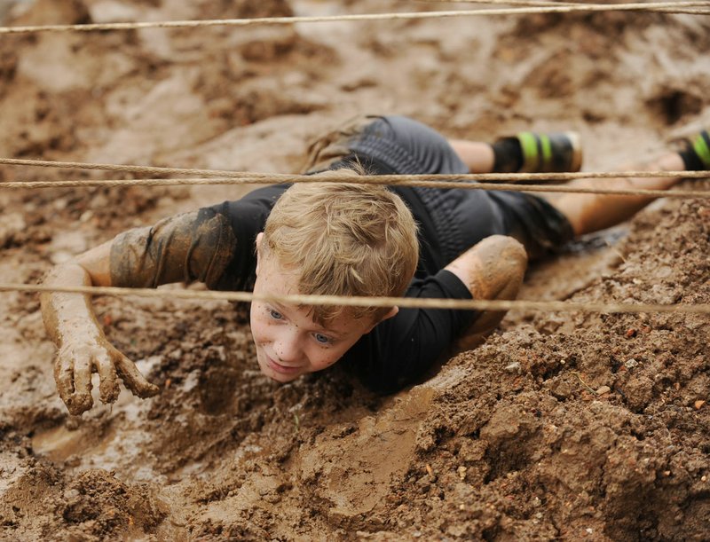 NWA Democrat-Gazette/ANDY SHUPE Cooper Claussen of Springdale laughs as he crawls through mud during the 2015 Pig Trail Mud Run at the Ecclesia College campus in Elm Springs. This year’s event on June 3 supports Springdale Rotary Club’s third-grade literacy project.