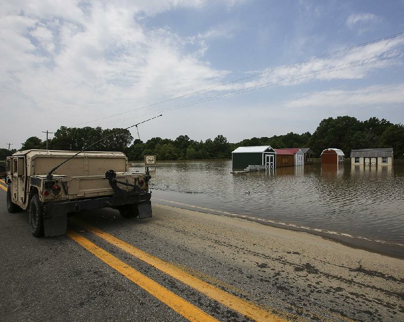 A National Guard Humvee drives past a !ooded business Thursday on Arkansas 38 east of Des Arc. The White River has dropped nearly a foot since Tuesday, when it crested at 35.5 feet.