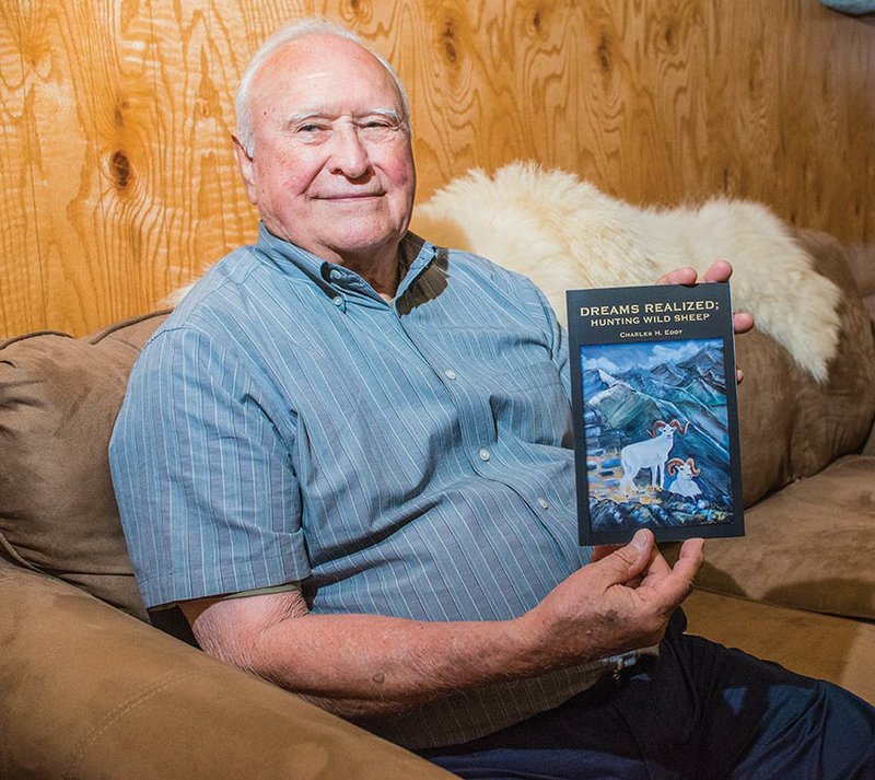 Charles H. Eddy holds the book he published, Dreams Realized: Hunting Wild Sheep, with the accounts of his adventures as a big-game hunter. Eddy said he is giving the book away to friends, family and anyone who would like to read about his hunting trips to Canada, Alaska and Wyoming. His wife, Jeanette, painted the sheep that he used for the cover illustration.