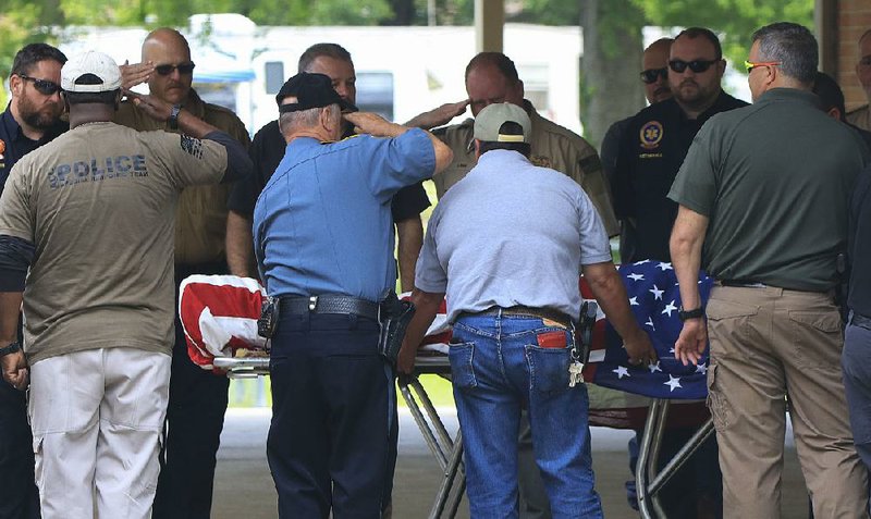 Law enforcement officers salute as the body of Yell County sheriff’s deputy Lt. Kevin Mainhart is moved from a hearse into a funeral home in Dardanelle on Friday afternoon. Mainhart was killed Thursday during a traffic stop. 