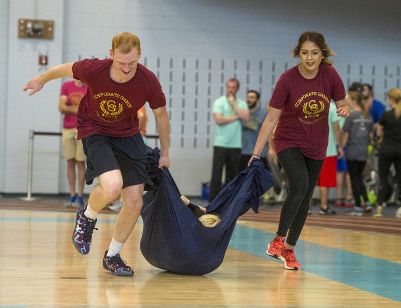 Dylan Shade (left) and Denyse Leon (right) pull co-worker Deanna Young, all with Spectrum Brands, during a part of a relay race Friday during the Corporate Games at The Jones Center in Springdale. Several companies competed against one another in a variety of games including volleyball, relay racing, broomball and battleship.