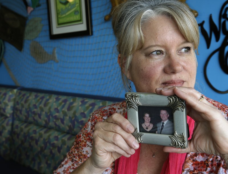 In this April 27, 2017 photo, Susan Jones poses for a photo in a restaurant in Long Beach, Wash., as she holds a picture of herself with her husband Martin Jones, who was convicted in the Feb. 13, 2010 shooting of Scott Johnson, who was then a Washington state trooper. Martin Jones' attorneys are now seeking a new trial and Johnson is now the Pacific County Sheriff.