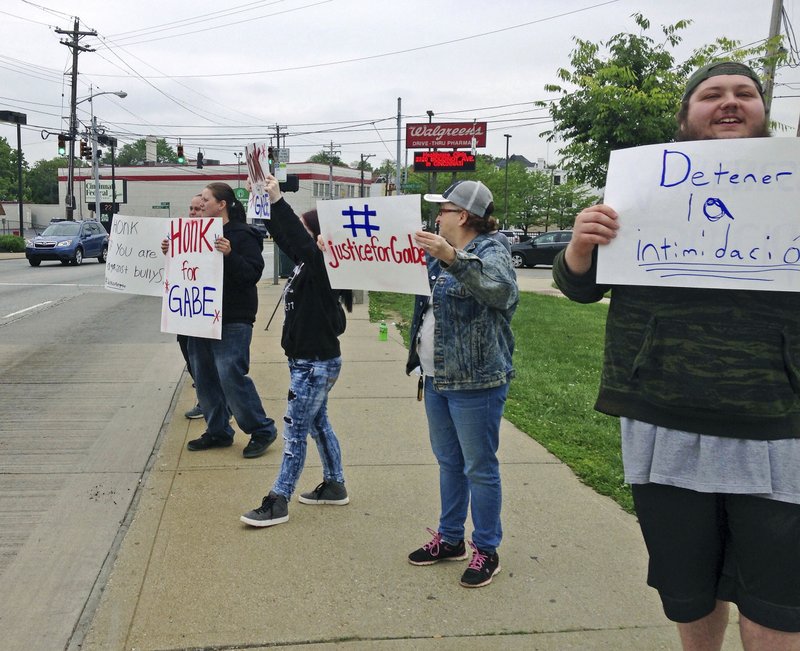 Parents and other demonstrators hold signs against bullying and in memory of Gabriel Taye, an 8-year-old boy who killed himself in January 2017 two days after being knocked unconscious by another Carson School student, on Friday, May 12, 2017, outside the elementary school in Cincinnati. Cincinnati Public Schools released a 24-minute surveillance video Friday that appears to show Gabriel trying to shake the hand of a boy who had hit another child, and then collapsing to the floor after being pushed into a wall at the entrance of a boys' bathroom. 