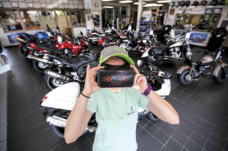 Treva Dillon of Cabot takes a simulated ride with a virtual reality viewer at Doug Reynolds Suzuki in Little Rock. 