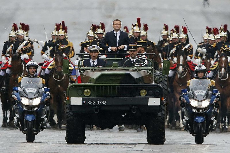 French President Emmanuel Macron, after taking office Sunday, rides in a military procession through Paris along the Champs Elysees to the Tomb of the Unknown Soldier at the Arc de Triomphe.