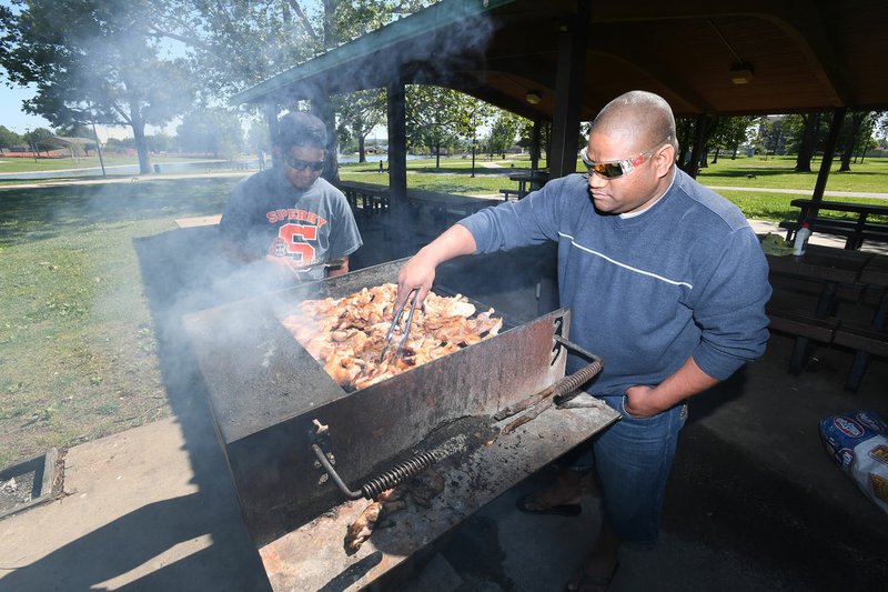 Fredrick Jekkein, (right) and Marrel Jeik, both of Springdale, grill chicken Saturday at Murphy Park in Springdale. The men are originally from the Marshall Islands and were at the park to celebrate Mother’s Day with family. The city will hold Murphy in May on Friday to celebrate renovations to the park.