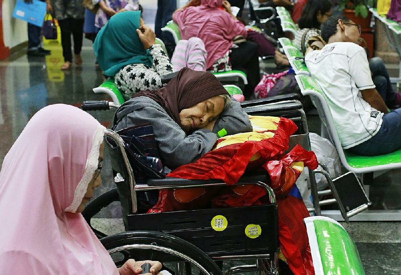 A patient takes a nap in her wheelchair as she waits Monday with others at the registration desk at Dharmais Cancer Hospital in Jakarta, Indonesia, after the hospital’s information system was affected by the global cyberattack.