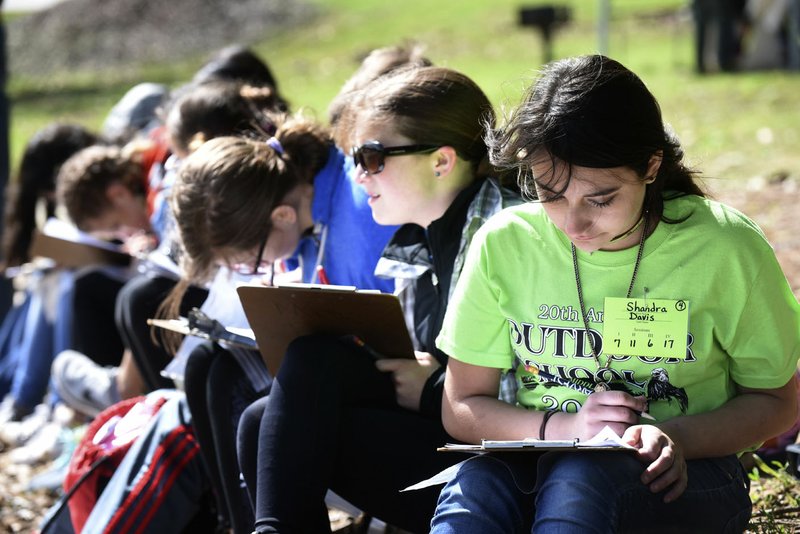 Shandra Davis (right) and Makayla Wolfe (second from right) work on their outdoor stories at the 20th annual Lingle Middle School Outdoors School at Prairie Creek park at Beaver Lake.