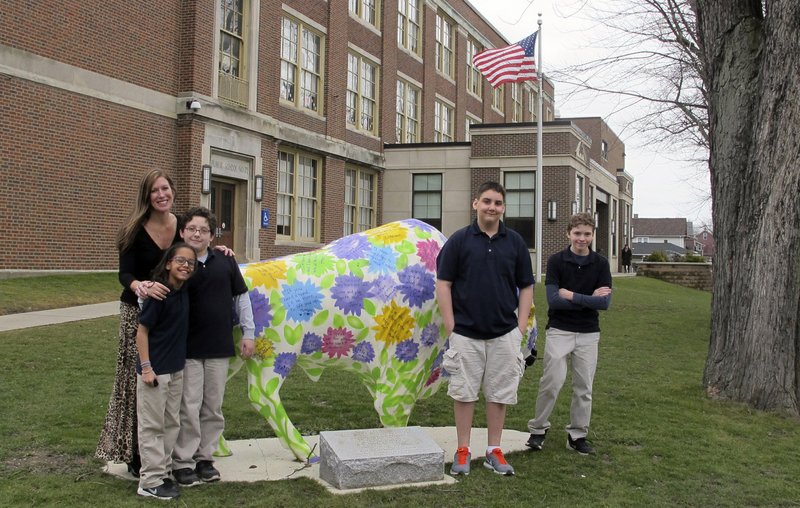 In this Feb. 29, 2016 file photo, teacher Kelly Gasior, left, and students, from left, Olivia Mashtaire, Ryan Lysek, Christian Vazquez and Tyler Lysek stand with a statue of a Buffalo that's been emblazoned with anti-bullying messages outside Lorraine Academy, Public School No. 72, in Buffalo, N.Y. 