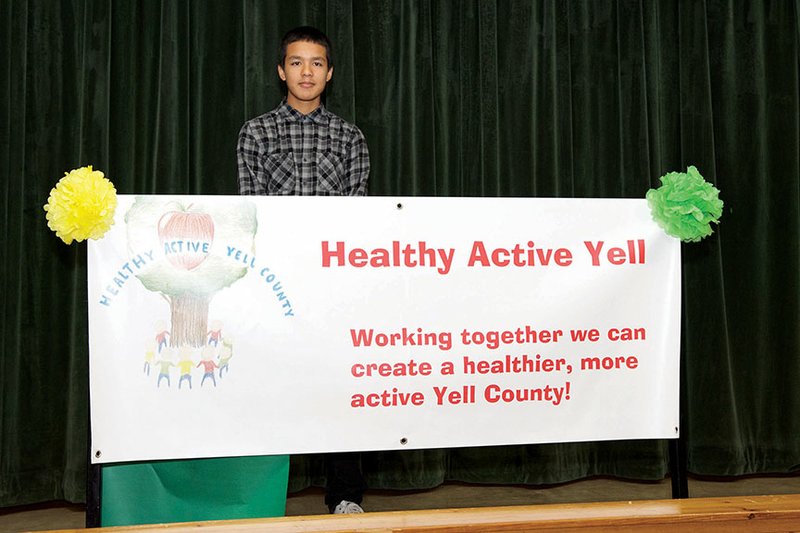 Danville High School sophomore Ivan Oblea stands with a banner showing his winning logo for Healthy Active Yell. The initiative was started by Cynthia Day, nurse practitioner for a clinic of Chambers Memorial Hospital in Danville. The Healthy Active Yell Committee includes representatives of four school districts, as well as other entities.