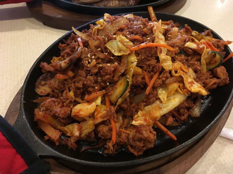 Jeyuk Bokkeum, spicy ground pork stir-fried with vegetables and served on a skillet, is among the Korean Specials at Kimchi on South University Avenue in Little Rock. 