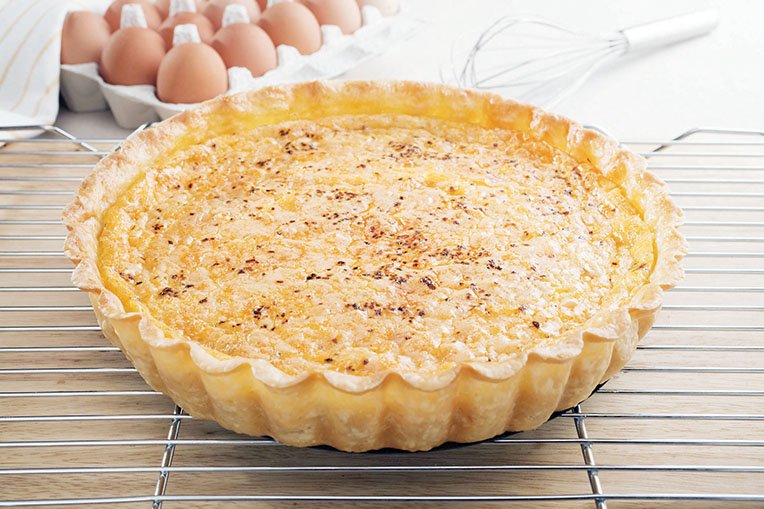 To serve, use a sharp, serrated knife to cut the warm quiche into wedges.