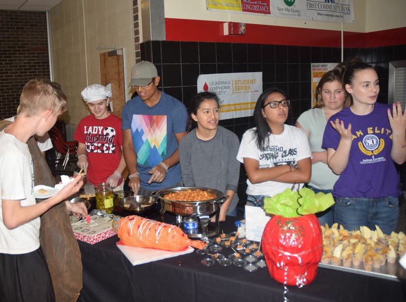 Francisco Jasso (in baseball cap) serves samples of his caliente jalapeno quesadillas to the students at McDonald County High School during lunch last week. Students in a nutrition and wellness class taught by Marie Strader developed five recipes that met federal regulations with the winning recipe to be included in next year&#8217;s lunch menu.