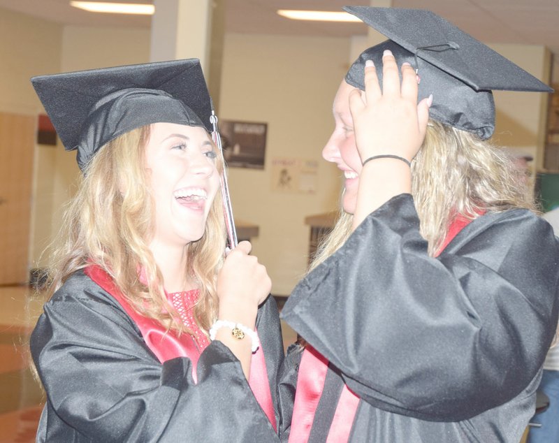 Addison Poland (left) and Paige Jones have a laugh prior to the May 13 graduation ceremonies of the class of 2017 from McDonald County High School.