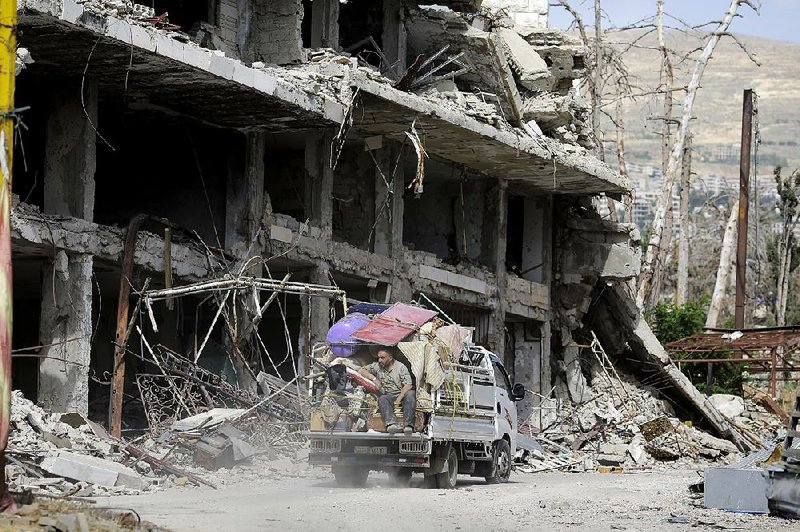 A Syrian man sits on the back of a truck Thursday after retrieving furniture from his destroyed house in the mountain resort town of Zabadani in the Damascus countryside of Syria. Meanwhile, a U.S. airstrike hit in the desert near the border with Jordan, though it was unclear whether it struck the Syrian army or just militias allied with the government. 