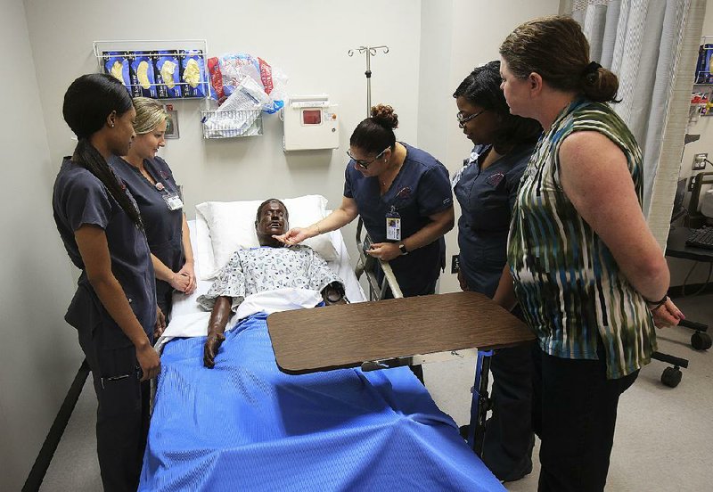 Assistant professor Sloan Davidson (right) keeps an eye on nursing students (from left) Tyler Simpson, Deziray Jackson, Karla Diaz-Claudio and Ashley Montgomery as they examine a mannequin Thursday on the University of Arkansas at Little Rock campus. 