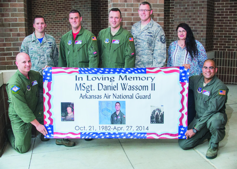 Joshua Taylor, from left, Brandon Lee, Steve Bryant, Shawn Engelstad and Travis Alkire stand next to Pam Wassom, the late Dan Wassom’s mother, with Joseph Taylor, holding up a banner displaying photos of Dan. Dan Wassom died while protecting his daughter, Lorelai, during the April 2014 tornado in Vilonia. The Awesome Wassom Kooky Costume 5K is dedicated to his memory.