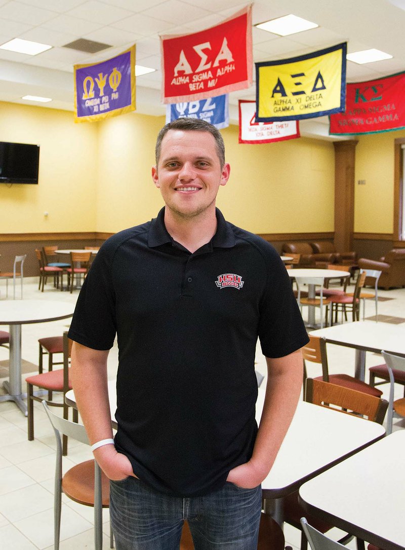 Keith Beason, standing in a dining area adorned with Greek-life symbols at Henderson State University, recently completed his first year as director of Greek life at the Arkadelphia college. Beason, a native of Redwater, Texas, is a 2009 graduate of Southern Arkansas University in Magnolia.