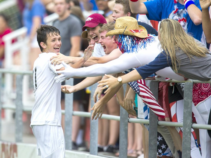 Eli Jackson of Siloam Springs (left) celebrates with fans after scoring his third goal Friday in the Panthers’ 4-0 victory over Mountain Home for the Class 6A state championship in Fayetteville. The Panthers set a single-season school record with 21 victories on their way to a second consecutive state title. 