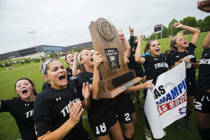 Bentonville players show off the Class 7A state championship trophy they won Saturday by beating Cabot 4-0 at Razorback Field in Fayetteville. The Lady Tigers won their second consecutive soccer state title.