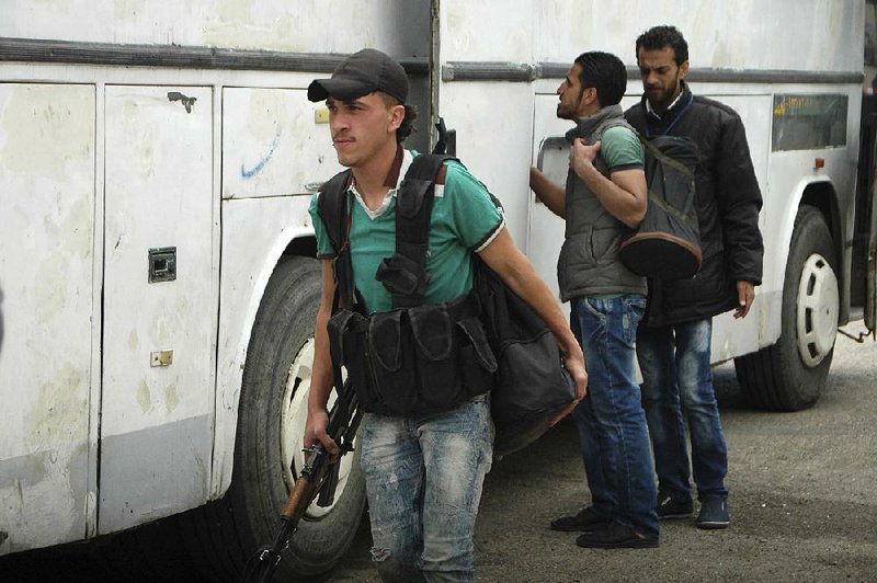 Armed Syrian opposition fighters prepare to board a bus Saturday to evacuate the besieged al-Waer neighborhood in the city of Homs. 
