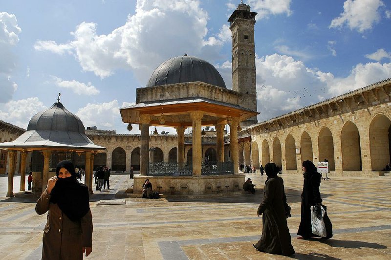 Visitors walk through Aleppo’s Umayyad mosque courtyard  n 2007 before Syria’s civil war. The mosque’s 150-foot minaret, in place since 1090, rises over the complex. 