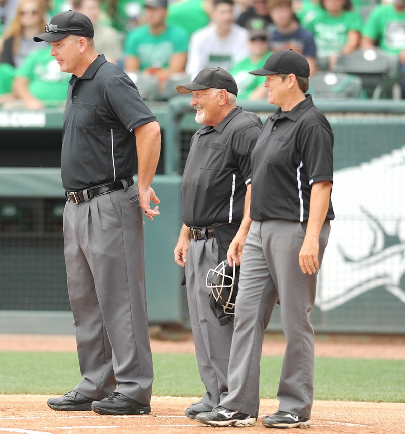 Umpires Laurie Adkins (from right), James Bryan and Chad Hipps await the start of the Class 3A state championship baseball game Friday at Baum Stadium in Fayetteville. Adkins became the first female umpire to call an Arkansas state championship baseball game.