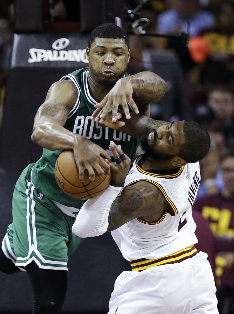 Boston’s Marcus Smart and Cleveland’s Kyrie Irving (right) battle for a first-half rebound in the Celtics’ 111-108 victory in Game 3 of their NBA Eastern Conference series Sunday in Cleveland. The loss by the Cavaliers was their first in this season’s playoffs after 10 consecutive victories over Indiana, Toronto and Boston.