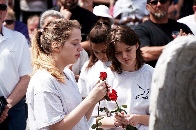 Students from John F. Deering Middle School in West Warwick, R.I., form a procession holding 100 roses, one for each victim of a 2003 nightclub fire, at the opening of the Station Fire Memorial Park.
