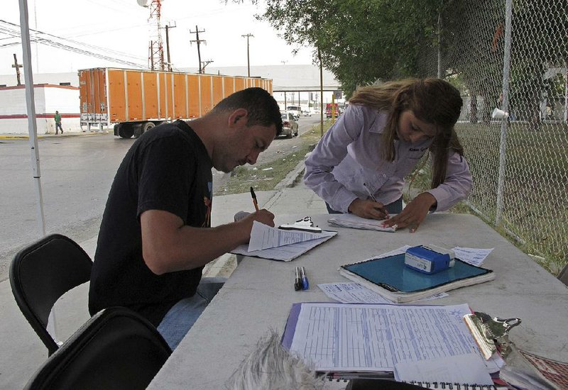 Aimee Gomez, a recruiter for assembly plants in Reynosa, Mexico, helps Juan Luis Alvarado de la Rosa fill out a job application last month in an industrial park across the border from McAllen, Texas.