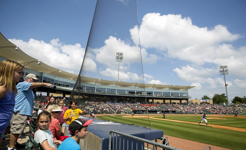 Fans watch from behind the netting, which was extended to the end of each dugout before this season, Tuesday during the Naturals’ game against the Arkansas Travelers at Arvest Ballpark in Springdale. The added netting was to help ensure fan safety at the ballpark, which is part of an initiative from Major League Baseball.