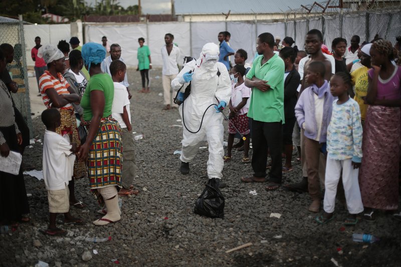 FILE - In this file photo dated Tuesday, Sept. 30, 2014, a medical worker sprays people being discharged from the Island Clinic Ebola treatment center in Monrovia, Liberia. The World Health Organization routinely spends about $200 million a year on travel, far more than what it doles out to fight some of the biggest problems in public health including AIDS, tuberculosis and malaria, according to internal documents obtained by The Associated Press, published Sunday, May 21, 2017. (AP Photo/Jerome Delay, File)