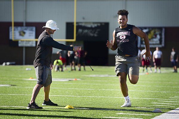 Brian Early, left, an assistant coach with Arkansas State times Isaiah Nichols of Springdale in the 40-yard dash, Tuesday, June 7, 2016, at Tiger Stadium in Bentonville. 
