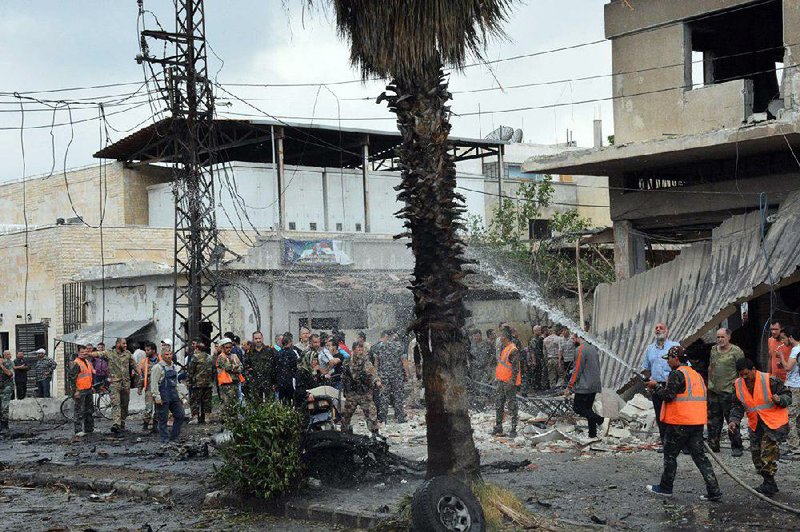 Syrian security forces and ÿreÿghters gather Tuesday at the scene of an explosion in the central city of Homs.