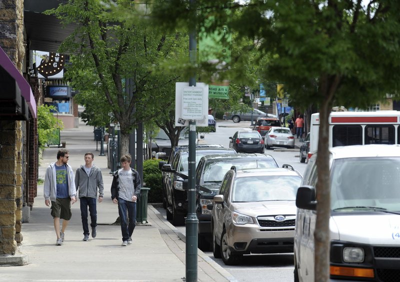 Pedestrians walk at midday Tuesday along Dickson Street in Fayetteville. Dickson Street Merchants Association released a survey concerning parking in downtown they compiled by polling 1,149 people during a two-week period in April.