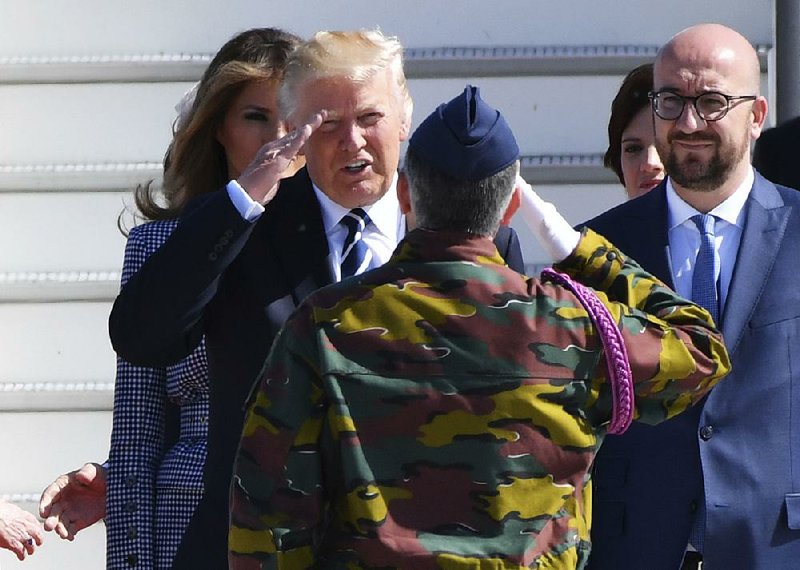 President Donald Trump salutes a Belgian soldier Wednesday as he and his wife, Melania, arrive at Meisbroek Military Airport in Belgium. At right is Belgian Prime Minister Charles Michel. Trump will meet with NATO allies today.