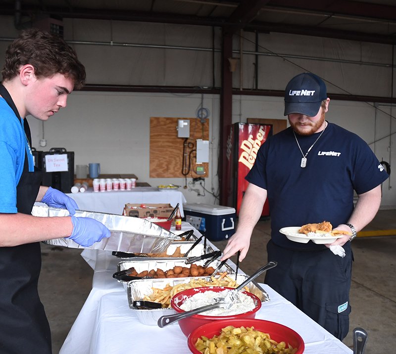 The Sentinel-Record/Mara Kuhn Dawson Lambert, left, with Woods Catering, prepares food Wednesday as Briar Jackson, a LifeNet dispatcher, fills his plate during LifeNet's annual fish fry to celebrate EMS Week. LifeNet holds the dinner each year for local law enforcement officers, fire department personnel and other emergency providers to show their appreciation.