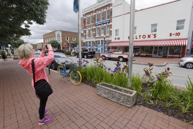 Maureen Jackson, visiting Bentonville from Iowa, takes pictures Wednesday on the town square. Bentonville had the largest growth rate and most new residents among Northwest Arkansas’ four largest cities.